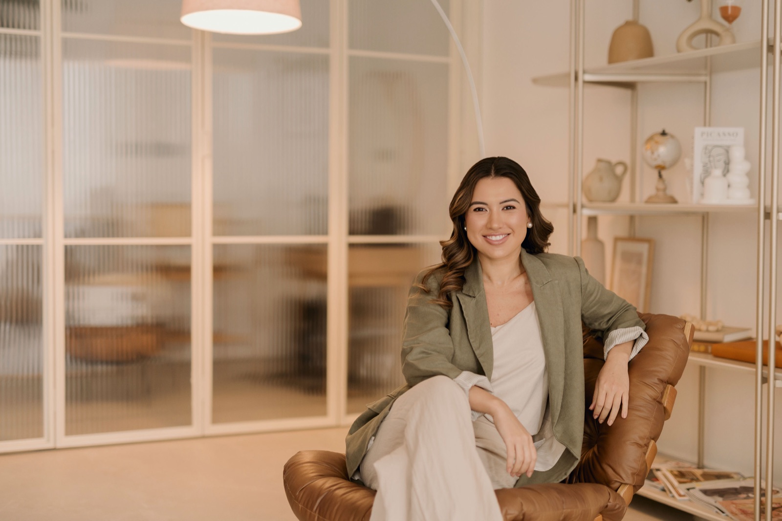 Dra. Monise Watanabe sentada em uma poltrona, sorrindo, em ambiente acolhedor